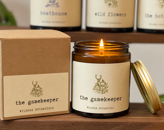 WILDOAK BOTANICALS THE GAMEKEEPER soy candle with frankincense, vetiver, and leather scent in a glass jar with a wooden lid