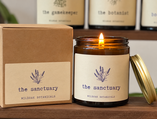 WILDOAK BOTANICALS Lavender, Lemon, Ylang Ylang essential oils soy candle with a clear glass jar and a lit wick.